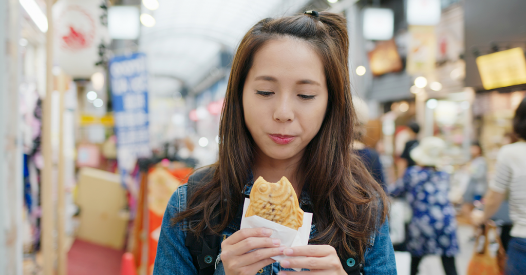 Imagen de una mujer comiendo Taiyaki en las calles de Japón